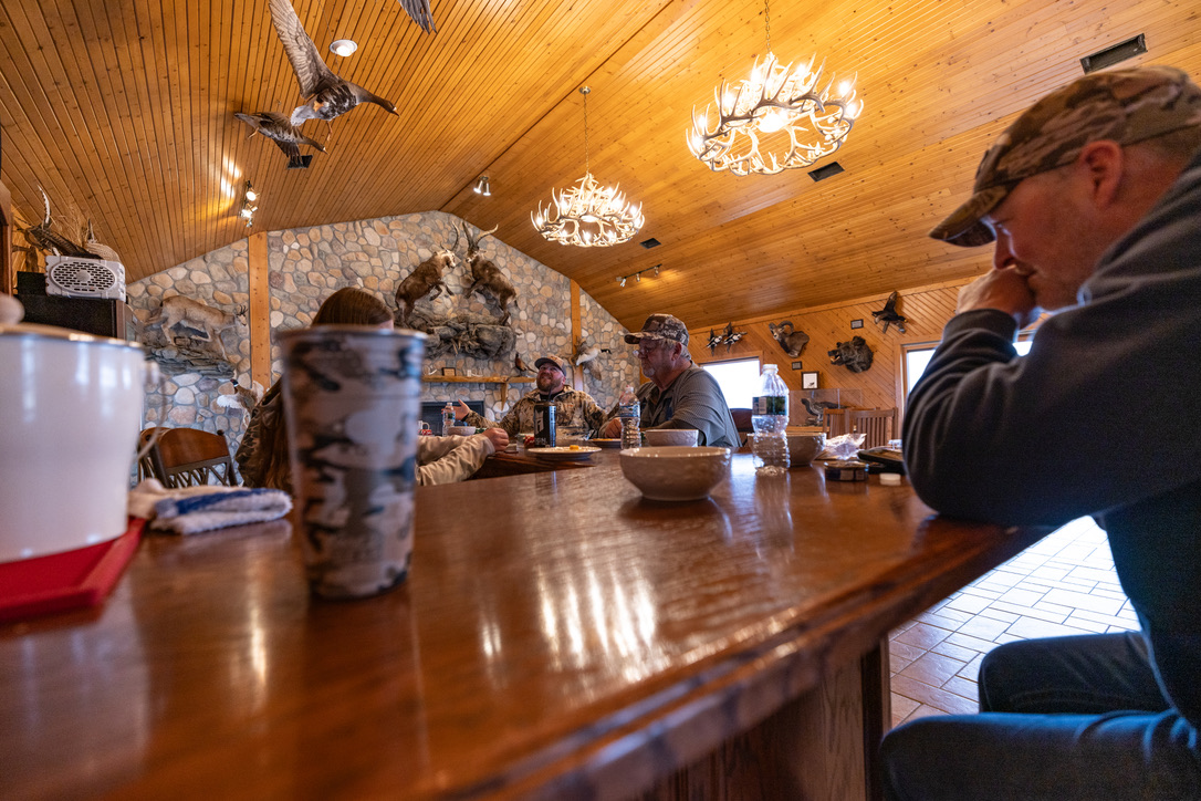 Guests eating along the lodge bar under antler chandeliers