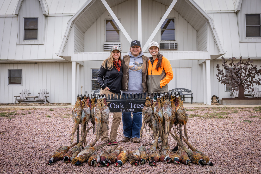 Three women hunters behind the Oak Tree sign with their limit