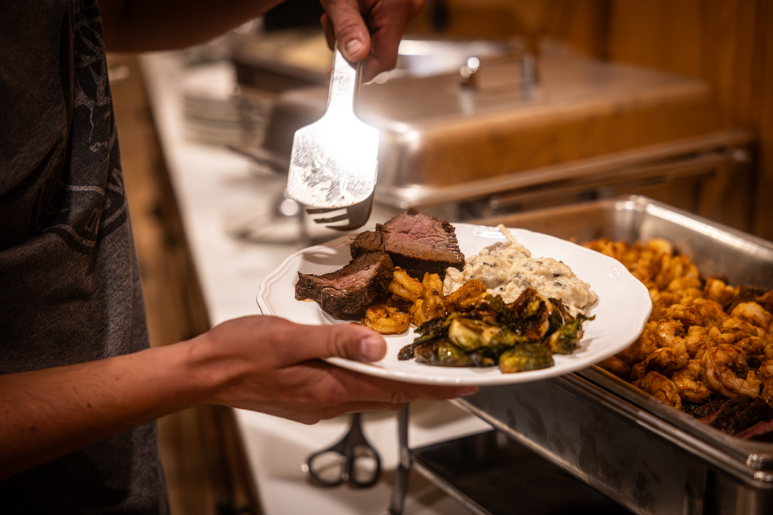A plated dinner of steak, shrimp, brussels, and potatoes