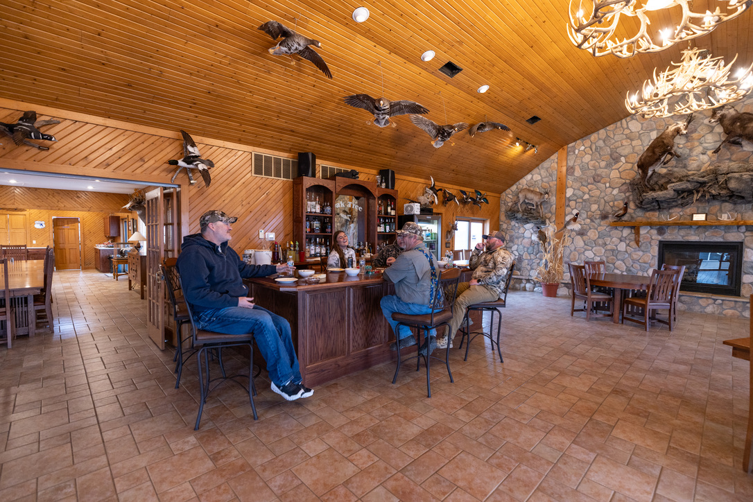 Wide view of the lodge bar under antler chandeliers and mounted birds